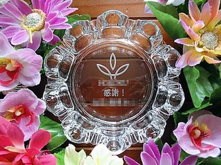 「ロゴマーク、感謝 ○○殿」を底面に彫刻した、永年勤続の記念品用のガラス製灰皿