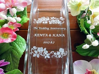 「The wedding anniversary」「奥さまと旦那様の名前」「結婚記念日の日付」「バラの花の飾り」を側面に彫刻した、奥さまへの結婚記念日のプレゼントのフラワーベース