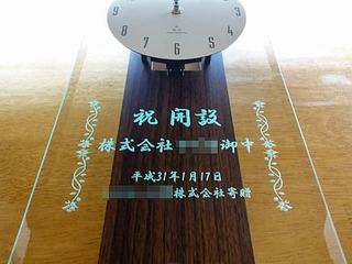 「祝開設 株式会社○○御中」を前面ガラスに彫刻した、事業所の開設祝い用の掛け時計