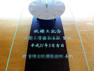「祝竣工記念、会社名、日付」を彫刻した、営業所の竣工祝い用の名入れ掛け時計