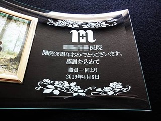 「ロゴマーク」と「お祝いメッセージ、病院名、日付」を彫刻した、職員一同から病院への周年祝い用の写真立て