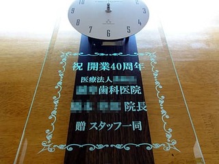 「祝 開業40周年、○○歯科医院、贈スタッフ一同」を彫刻した、歯科医院の周年祝い用の掛け時計