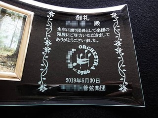 「名前と感謝を込めたメッセージ」「楽団のマーク」を彫刻した、管弦楽団を退団する方への贈り物用の写真立て