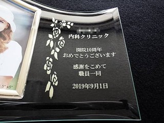 「○○内科クリニック開院10周年おめでとうございます。感謝を込めて、職員一同」を彫刻した、クリニックの周年祝い用のフォトフレーム