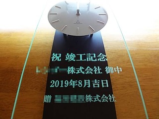 「祝竣工記念、○○株式会社御中、贈 株式会社○○」を彫刻した、お得意先への竣工祝い用の掛け時計