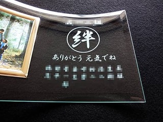 「絆」「ありがとう 元気でね」「職場のメンバー一同の名前」を彫刻した、退職する同僚への贈り物の写真立て
