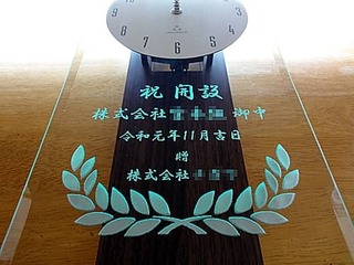 「祝開設、株式会社○○御中、贈○○株式会社」を彫刻した、事務所の開設祝い用の掛け時計