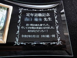 「定年退職記念 ○○先生 長い間お疲れさまでした。そして3年間お世話になりました。令和2年3月1日 3年3組一同」を彫刻した、担任の先生の定年退職祝い用のガラス製フォトスタンド