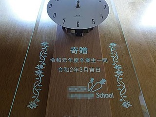 「学校のマーク」と「寄贈 令和元年度卒業生一同、令和2年3月吉日」を彫刻した、卒業生から学校へ寄贈する卒業記念品用の掛け時計