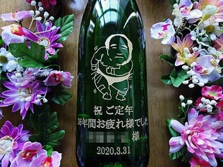 「定年退職する方の似顔絵」と「祝ご定年 36年間お疲れさまでした ○○様」を一升瓶の側面に彫刻した、定年退職祝い用の日本酒