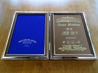「Happy wedding、新郎と新婦の名前、2020/4/3、贈○○一同」を彫刻した、結婚祝い用のブックタイプのフォトフレーム