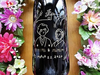 「お客様がデザインしたイラスト」と「新郎と新婦の名前、結婚式の日付」を側面に彫刻した、結婚祝い用の日本酒の一升瓶