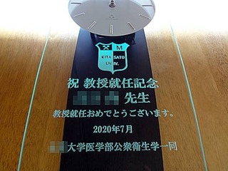 「大学のマーク」と「祝教授就任記念 ○○先生 ○○大学医学部公衆衛生学一同」を時計の前面ガラスに彫刻した、教授就任祝い用の掛け時計