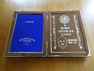 「園長先生の似顔絵と保育園のマーク」と、「祝園長就任 ○○先生 ○○保育園職員一同」を彫刻した、就任祝い用の写真立て