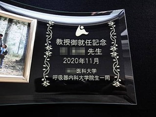 「大学のマークと、教授御就任記念 ○○先生 ○○医科大学○○科大学院生一同」を彫刻した、教授就任祝い用の写真立て