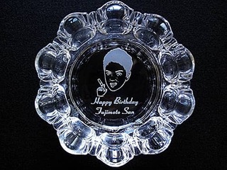 「Happy Birthday、贈る相手の似顔絵と名前」を底面に彫刻した、誕生日プレゼント用のガラス製灰皿