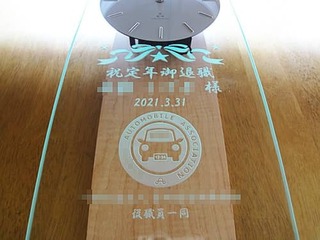「協会のマークと、祝定年退職 ○○様 ○○協会職員一同」を前面ガラスに彫刻した、定年退職祝い用の掛け時計