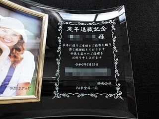 「定年退職記念 ○○様、感謝を込めたメッセージ、退職日の日付、会社のロゴ」を彫刻した、定年退職祝い用のガラス製写真立て