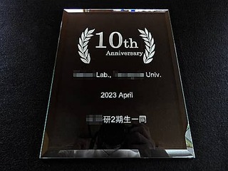 「10th anniversary ○○Lab.○○Univ. 、日付と贈り主の名前」を彫刻した、大学の研究室の10周年祝い用のガラス盾