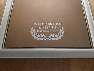 「祝 創業130周年記念、周年記念日の日付、贈り主の会社名」を表面に彫刻した、周年祝い用の鏡