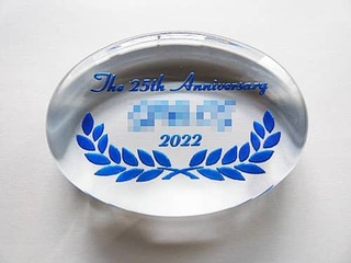 「The 25th Anniversary、会社名、日付」を彫刻した、25周年記念用のガラス製ペーパーウェイト