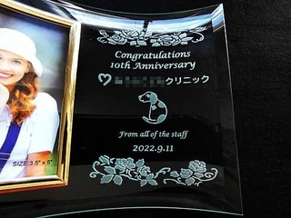 「Congratulations、10th Anniversary、クリニックのロゴとキャラクター」を彫刻した、スタッフからクリニックへの周年祝い用のガラス製写真立て