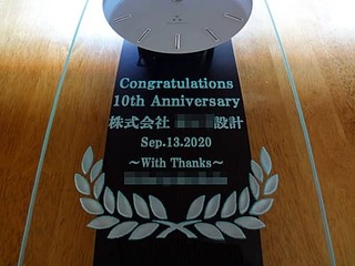 「Congratulations 10th Anniversary、株式会社○○設計、贈り主の名前」を前面ガラスに彫刻した、設計会社の周年祝い用の掛け時計