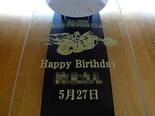 「趣味サークルのマーク、Happy Birthday、サークルメンバーの名前、誕生日の日付」を前面ガラスに彫刻した、誕生日プレゼント用の振り子時計