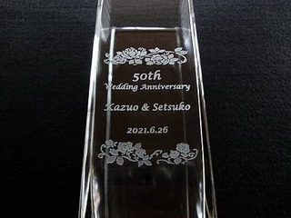 「50th Wedding Anniversary、旦那様と奥さまの名前、結婚記念日の日付」を側面に彫刻した、金婚式祝い用の角柱型フラワーベース