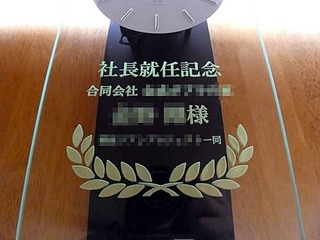「社長就任記念、合同会社○○、○○様、○○一同」を前面ガラスに彫刻した、社長就任祝い用の振り子時計
