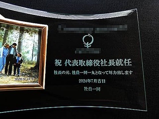 会社のロゴマーク、祝 代表取締役社長就任、就任日の日付、贈り主の名前を彫刻した、社長就任祝い用のガラス製写真立て
