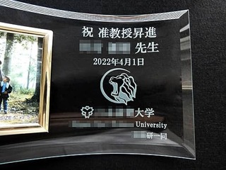 「祝准教授昇進 ○○先生 2022年4月1日 ○○大学○○研一同」と「大学のシンボルマスコット」を彫刻した、准教授昇進祝い用の写真立て