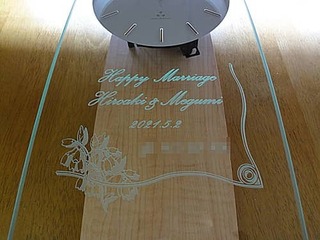 「Happy marriage、新郎と新婦の名前、結婚式の日付、贈り主の名前」を前面ガラスに彫刻した、結婚祝い用の掛け時計
