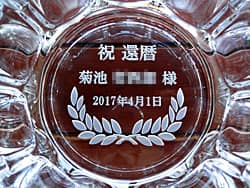 「祝還暦、○○様、日付」を彫刻した、還暦祝いの贈り物用の灰皿