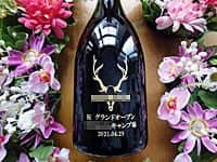 キャンプ場の開業祝い用のシャンパン(キャンプ場のロゴマーク、祝グランドオープン ○○キャンプ場、日付をボトル側面に彫刻)
