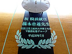 「祝 院長就任 ○○先生、日付」を前面ガラスに彫刻した、病院長就任祝い用の掛け時計
