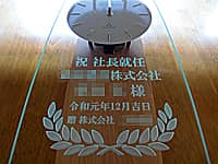 「祝社長就任 ○○株式会社 ○○様、令和元年12月吉日、贈 株式会社○○」を彫刻した、就任祝い用の掛け時計