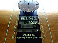 「祝議長就任 ○○市議会議員○○様 ○○会 令和元年6月」を前面ガラスに彫刻した、市議会の議長就任祝い用の掛け時計