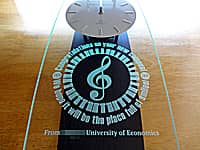 大学の新キャンパス開設祝い用の掛け時計(音符と鍵盤のイラストと、Congratulations on your new campus. We hope it will be the place full of smiles. From ○○ Universityを前面ガラスに彫刻)