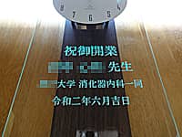 クリニックの開業祝い用の掛け時計(祝御開業、○○先生、○○大学消化器内科一同、令和二年六月吉日を、掛け時計の前面ガラスに彫刻)