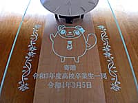 「学校のマスコットキャラクター」と「寄贈 令和3年度高校卒業生一同、卒業式の日付」を前面ガラスに彫刻した、卒業生から高等学校へ寄贈する掛け時計