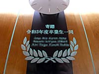 「寄贈 令和3年度卒業生一同、クラス全員の名前」を前面ガラスに彫刻した、卒業生から小学校へ寄贈する振り子時計