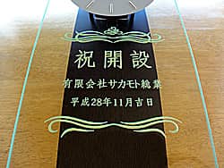 「祝開設、会社名、日付」を前面ガラスに彫刻した、営業所の開設祝い用の掛け時計