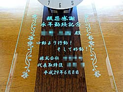 「名前、会社のスローガン、会社名」を前面ガラスに彫刻した、永年勤続の記念品用の掛け時計