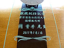 「教授就任記念 ○○先生、大学名」を前面ガラスに彫刻した、教授就任のお祝い品用の掛け時計