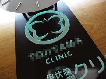 掛け時計の前面ガラスに彫刻したクリニックのロゴマークのクローズアップ画像