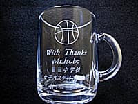 「バスケットボールのイラスト」と「With thanks、先生の名前、学校名、日付」を彫刻した、卒業生から部活の先生へ贈るガラス製マグカップ