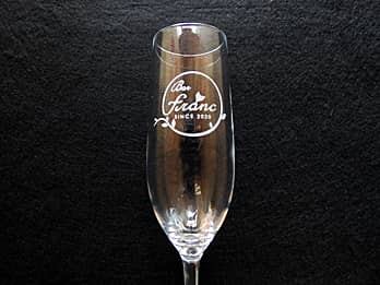 ���H�X�̃��S�}�[�N�𑤖ʂɒ��������A���X�̎��N�L�O�i�p�̃V�����p���O���XG-2