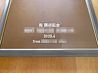 「祝 開店記念、店名、開店日の日付、贈り主の名前」を表面に彫刻した、開店祝い用の鏡