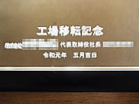 「工場移転記念、株式会社○○代表取締役○○、日付」を彫刻した、お取引先の工場移転祝い用の鏡
